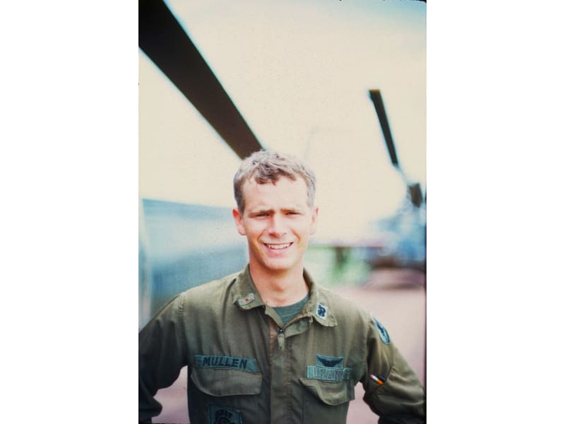 A man in military fatigues standing next to an airplane.